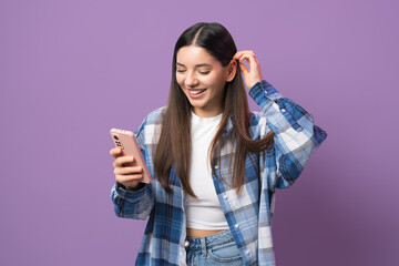 Young and enthusiastic woman scrolling music on her phone while putting her hair behind ear with...