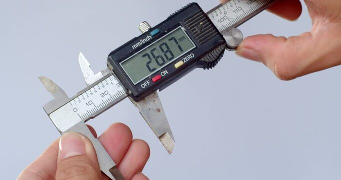 Hand of mechanic holding Vernier Caliper.The hand of the engineer measure digital vernier caliper against the white background