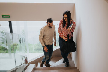 Young couple walking down stairs together in a modern home environment.