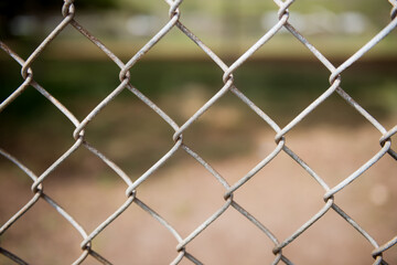 Fototapeta premium Fence with metal grid in perspective. Metal chain-link fence as the background, street photo, close-up,