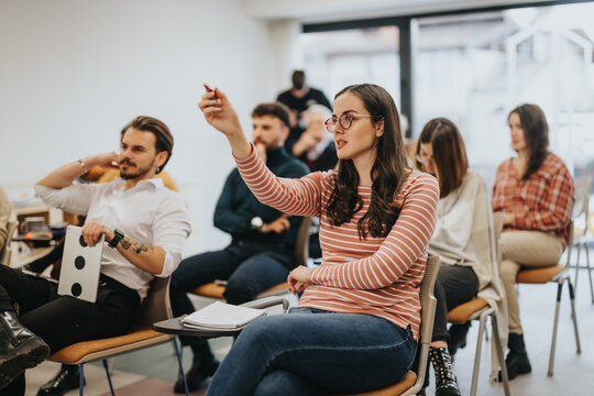 Engaged audience in an interactive workshop or business meeting raising hands.