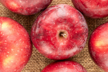 Several red apples  on jute cloth, macro, top view.
