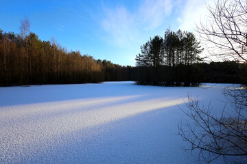 Frozen lake covered with snow in the forest in Scotland, UK