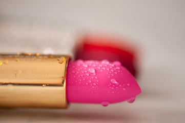Colorful lipsticks with drops of water on them closeup. Fashionable.