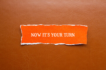 Now it's your turn lettering on ripped orange paper piece with brown background. Conceptual...