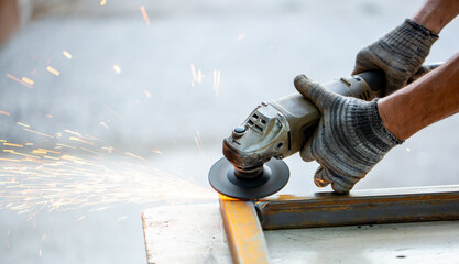 Grinding machine at work. Sparks fly from under the grinders, men's work. Dark background with copy...