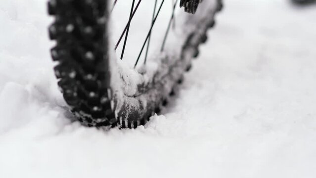 Close-up of a bicycle wheel spinning in the snow. The bicycle does not move due to a thick layer of snow on the road. Slow Motion 2x