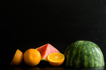 Wet Watermelon and Oranges Halves on Black Background