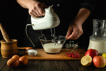 Chef prepares an egg omelette with milk using a hand-held electric mixer. Concept of preparing...