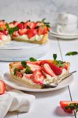 Slice of strawberry tart with butter cream on a white wooden table. French delicious dessert. Fresh and beautiful tart.