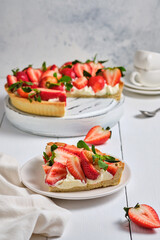 Slice of strawberry tart with butter cream on a white wooden table. French delicious dessert. Fresh and beautiful tart.