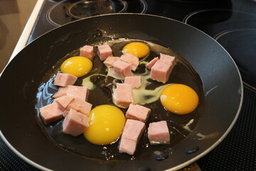 A pan with eggs and bacon is on the stove. Raw eggs and bacon in a pan.