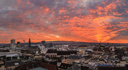 Burning sunset over the Swiss old city Basel in the dusk viewed high above on the Munster Church...