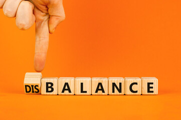 Balance or disbalance symbol. Concept word Disbalance or Balance on beautiful wooden cubes. Beautiful orange background. Businessman hand. Business balance or disbalance concept. Copy space.