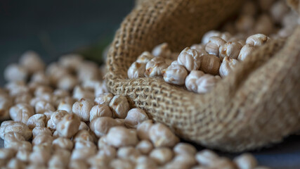
Raw chickpeas coming out of a sack and spread on a table
