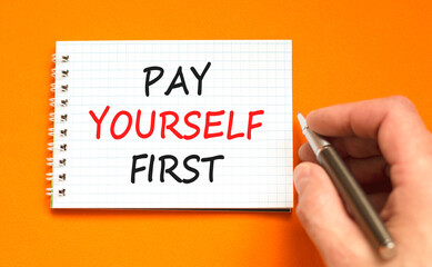 Pay yourself first symbol. Concept words Pay yourself first on beautiful white note. Beautiful orange background. Businessman hand. Business and pay yourself first concept. Copy space.