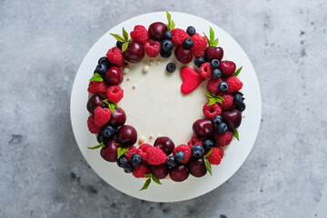 Delicious and beautiful handmade cake. Confectionery for the holiday. The dessert is decorated with fresh raspberries, cherries and blueberries.