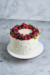 Delicious and beautiful handmade cake. Confectionery for the holiday. The dessert is decorated with fresh raspberries, cherries and blueberries.
