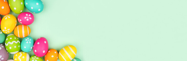 Fototapeta na wymiar Colorful Easter Egg top corner over a soft green paper banner background. Copy space.