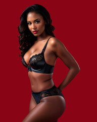 Fototapeta na wymiar Woman posing sexily in black lingerie, showing off her elegant curves and self-confidence on red background