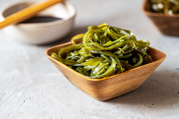 Wooden Bowl of Seaweed Salad with Chopsticks, soy sauce behind