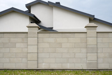 fence made of natural stone on the background of a newly built house