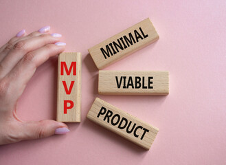 MVP - Most Valuable Player symbol. Wooden cubes with words MVP. Businessman hand. Beautiful pink background. Business and MVP concept. Copy space.