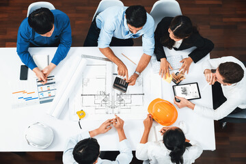 Fototapeta na wymiar Top view banner of diverse group of civil engineer and client working together on architectural project, reviewing construction plan and building blueprint at meeting table. Prudent