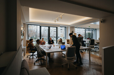 Diversity and teamwork in a modern office setting. A group of professionals sits at a table discussing projects with enthusiasm and focus.