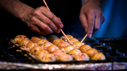 A Japanese vendor prepare a Takoyaki on hot pan food Japan. Fried octopus balls