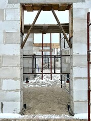 House building in progress - close front view of freshly built walls with brick concrete elements and builders' equipment.