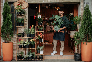 Young man smiles in plant store..concept: small plant and nursery business.
