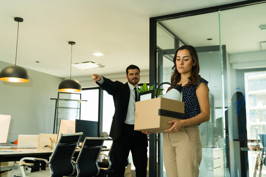 Hispanic woman getting fired from work and carrying a box of personal belongings