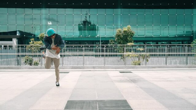 Happy hipster listen to hip hop music from headphone while dancing in lively mood. Professional street dancer perform b boy dancing at outdoor. Outdoor sport 2024. Modern lifestyle. Sprightly.