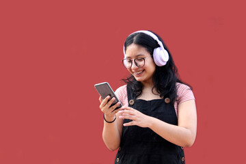 Female Latina teenager of 17 years old uses her cell phone and audio to connect to music, podcast audiobooks and songs with her friends