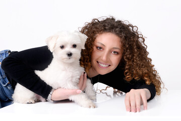 Girl with curly hair with a Maltese dog on a white background