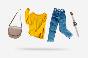 Yellow flying sweater,blue jeans,bag and watches flying on grey background. Trendy casual female clothing set. Women's clothes. © nys
