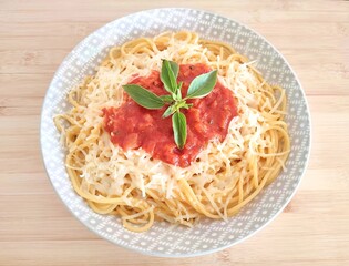 Top view of a simple pasta plate with tomato sauce and basil flavoring.