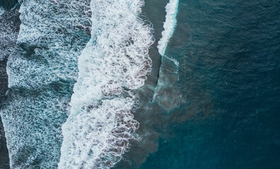 Aerial view of sea waves crashing leaving a trail of foam