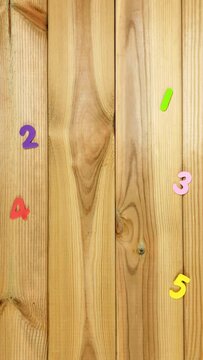 Numbers from 1 to 5.  Multi-colored numbers dance and line up in order on a wooden table. Stop motion animation for elementary school, advertising, educational programs for children.
