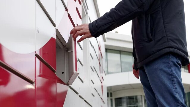 The young man opens the mailbox and takes the package.