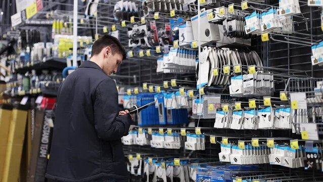 A young man examines the goods holding it in his hands.