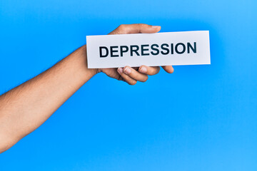Hand of caucasian man holding paper with depression word over isolated blue background