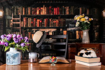 Easter jelly beans and spring flowers on wood table with sleeping cat and antique radio with old library background