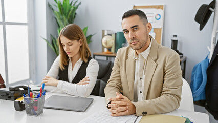 Focused woman and watchful man, co-workers in a modern office, reviewing documents at a white desk.