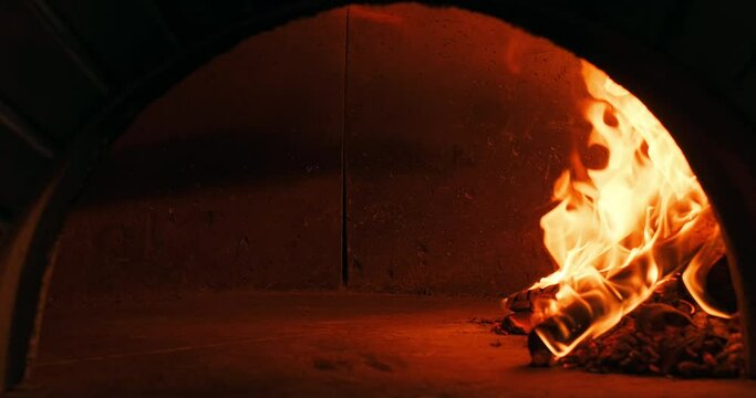 Firewood burning in a stone oven in a restaurant's bakery to bake pizza. Burning fire in stone oven. Traditional Italian pizzeria