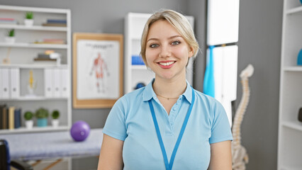 A professional young woman with a friendly smile wearing a blue polo stands confidently in a...