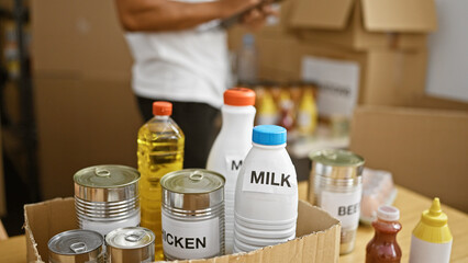 A young man organizes canned goods and bottles in a warehouse for distribution.