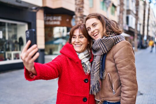 Two women mother and daughter make selfie by smartphone at street
