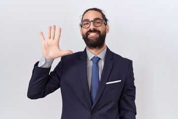 Hispanic man with beard wearing suit and tie showing and pointing up with fingers number five while smiling confident and happy.